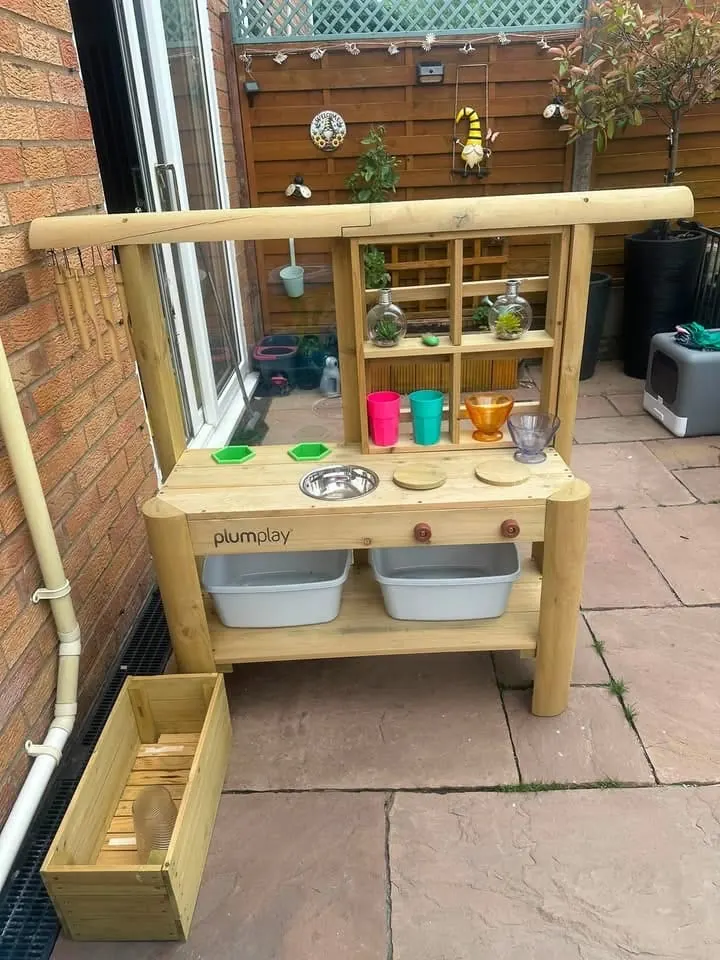 The wooden mud kitchen outdoors with bowls, pots and utensils ready for messy play